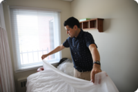 Homme préparant un lit dans une clinique médicale.