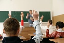 Élèves avec la main levée en classe.